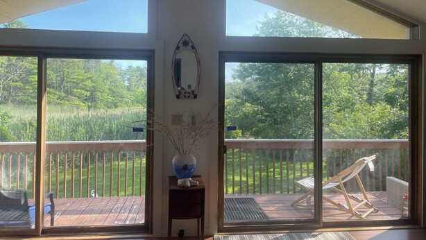 Une pièce dotée de grandes portes-fenêtres coulissantes qui donnent sur une terrasse extérieure, où se trouvent un hamac et un fauteuil.