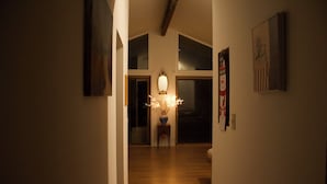 Un couloir doté d’un plancher en bois, d’un luminaire décoratif et d’un tableau encadré accroché au mur.