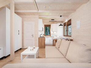 Ein modernes Interieur mit Holzboden, einer Couch, einem Esstisch und einer Küchenzeile.