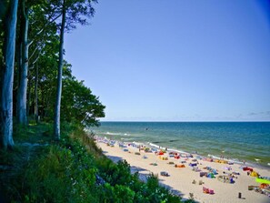 Ein Strand mit vielen bunten Sonnenschirmen und Badegästen.