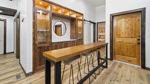 A bar area with stools, a wooden counter, and a large mirror. - Serene Ellijay Getaway with Coffee Bar, Two Fireplaces, Hot Tub, Games  + Resort (Ellijay)