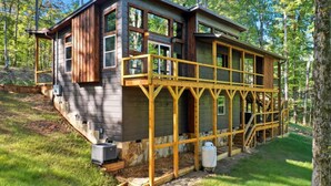A two-story cabin with a balcony, surrounded by trees. - Serene Ellijay Getaway with Coffee Bar, Two Fireplaces, Hot Tub, Games  + Resort (Ellijay)