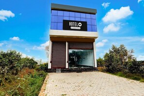A modern hotel with a prominent 'HOTEL' sign, a glass entrance, and a paved driveway. - Hotel O Naroli Crossway Mathura (Mathura)