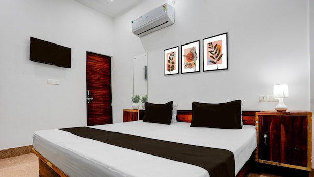 Ein Hotelzimmer mit Bett, Fernseher, Spiegel, Wandklimaanlage und gerahmten Bildern.