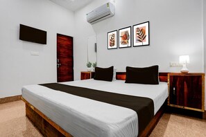 A hotel room with a bed, a TV, a mirror, a wall-mounted air conditioner, and framed artwork. - Hotel O Naroli Crossway Mathura (Mathura)