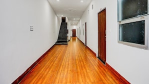 Ein langer, schmaler Korridor mit Holzboden, weißen Wänden und einer Treppe am Ende.