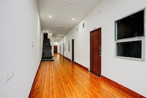 A hallway with wooden flooring, white walls, and a staircase at the end. - Hotel O Naroli Crossway Mathura (Mathura)