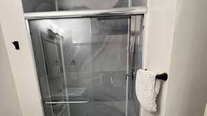 Eine begehbare Dusche mit Glastür, einem Handtuchhalter und Fliesen mit Muster.
