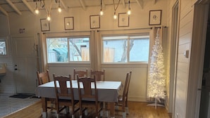 Ein Essbereich mit einem Holztisch und Stühlen, gerahmten Bildern an der Wand und einem weißen Weihnachtsbaum.