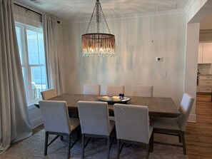 Ein Essbereich mit einem Holztisch, sechs Stühlen, einer Pendelleuchte und Blick durch ein Fenster.