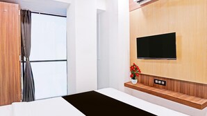 Quarto de hotel moderno com uma cama grande, televisão fixada na parede e um painel de parede de madeira.