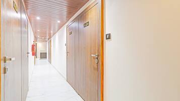 A hallway with wooden doors, numbered signs, and a white tiled floor.