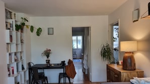 Un espace de vie compact comprenant un coin repas, un canapé, une lampe et une bibliothèque.