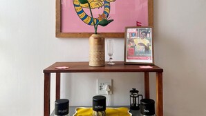 A framed tiger artwork on a wall, a wooden console table with a vase, a framed magazine, and two containers labeled 'sugar' and 'tea' on the console. - Jozi Muse: Retro Oasis in the Heart of Sandton (Sandton)