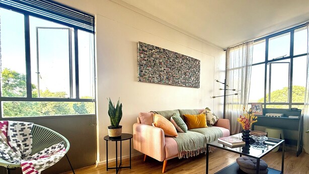 A living room with a sofa, a chair, a coffee table, and a potted plant. - Jozi Muse: Retro Oasis in the Heart of Sandton (Sandton)