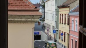 Una vista dalla finestra su una strada con edifici, un veicolo parcheggiato e un segnale di divieto di sosta.