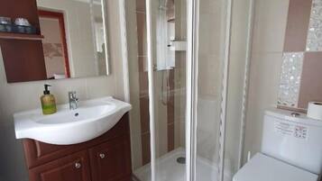 Un baño con ducha de vidrio, lavamanos, inodoro y espejo.