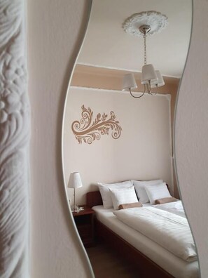 Un dormitorio con cama, mesita de noche, lámpara y un adorno en la pared.