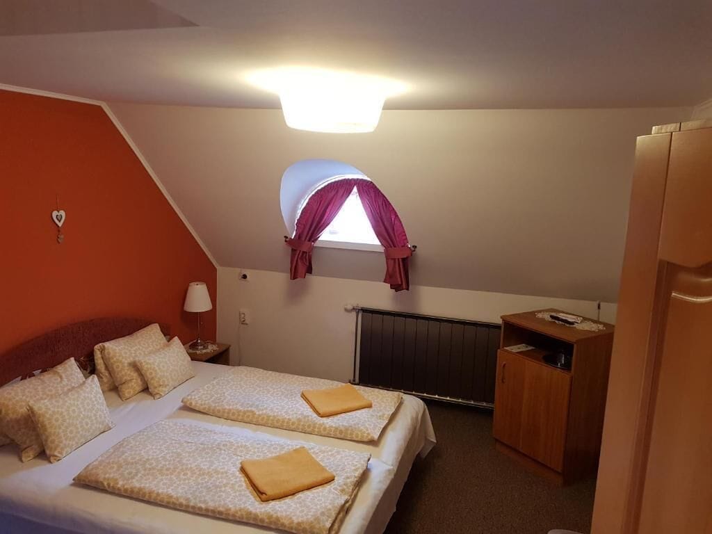 Un dormitorio con dos camas, un escritorio pequeño, un radiador y una ventana con cortinas.