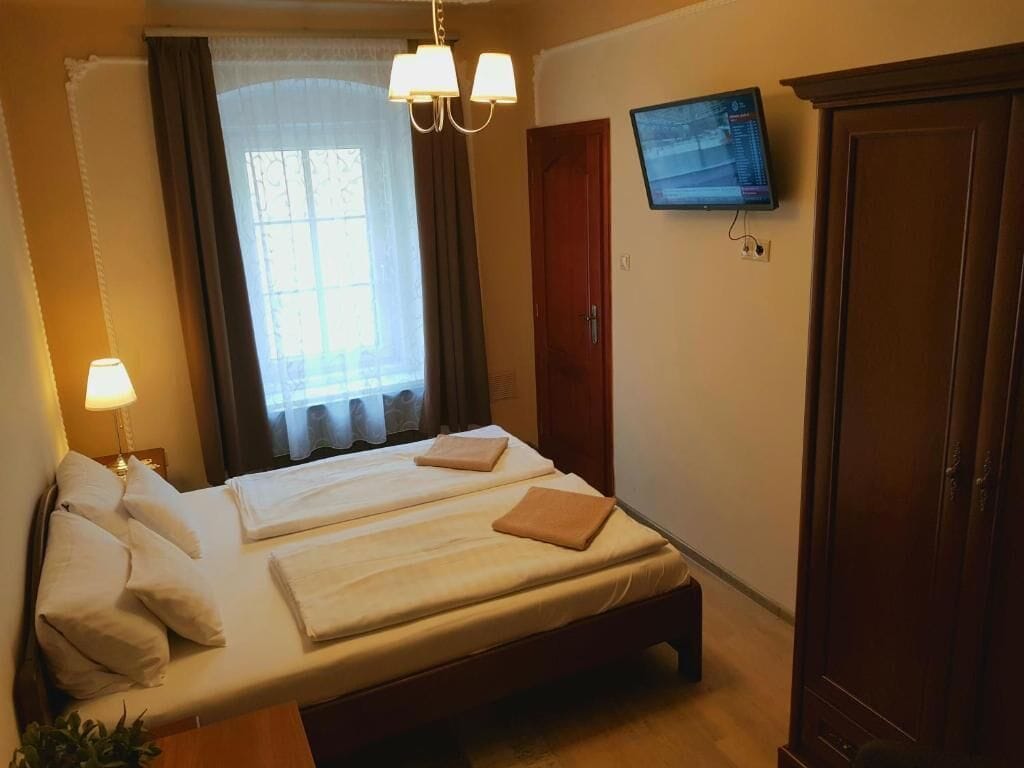 Habitación de hotel con dos camas, televisión, armario y ventana con cortinas.