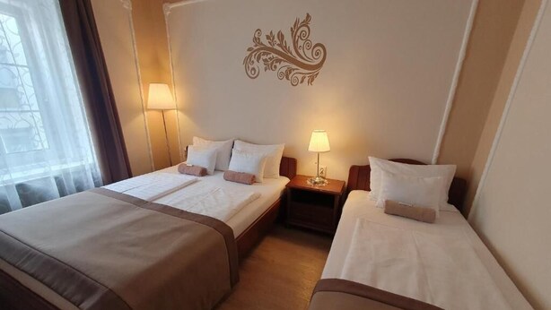 Una camera d'albergo con due letti, un elemento decorativo a parete e due lampade da comodino.