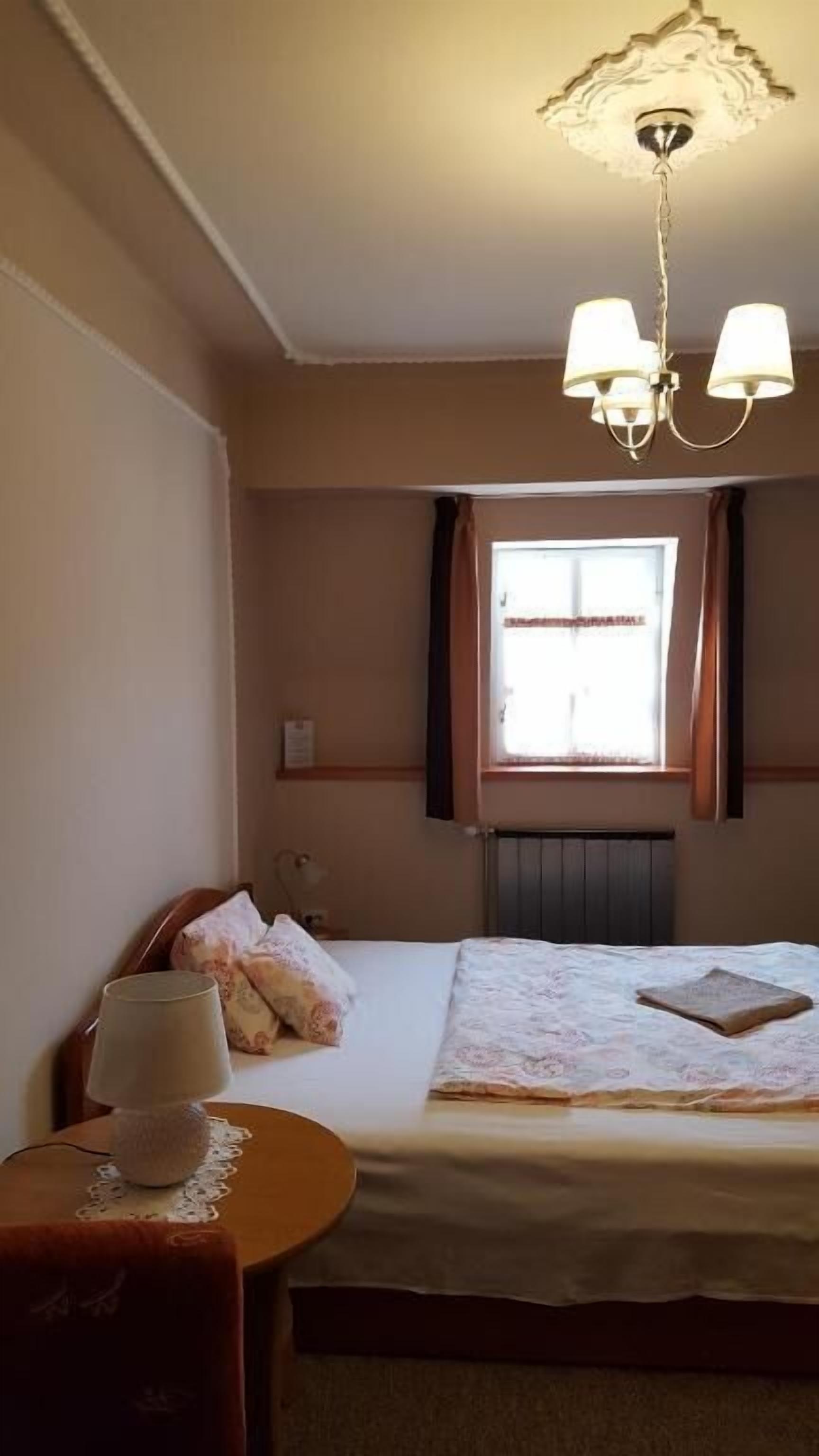 Une chambre à coucher avec un lit, une table de chevet, une lampe et une fenêtre avec des rideaux.