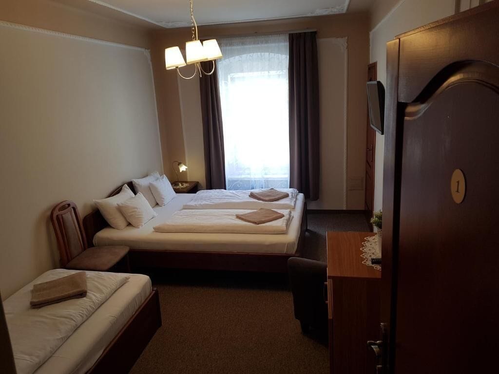 A hotel room with two beds, a desk, a chair, a wardrobe, and a window with curtains.