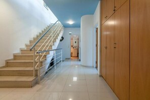 Ein Flur mit Treppe, Holzschränken und Fliesenboden.
