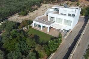 Ein modernes, zweigeschossiges Haus mit Flachdach, großen Fenstern und einer überdachten Terrasse.