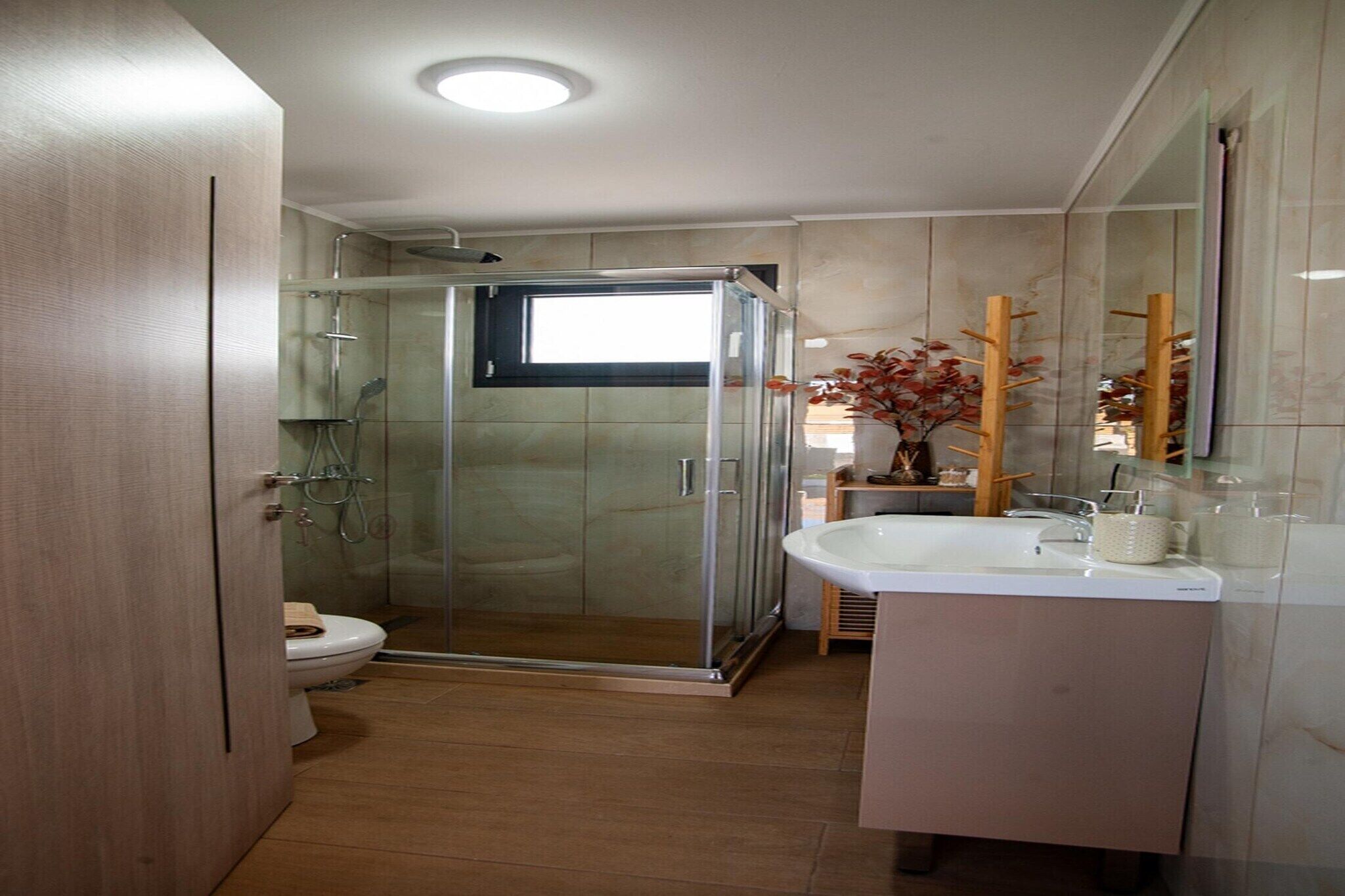 Une salle de bain moderne avec une douche à parois de verre, des toilettes et un lavabo avec un miroir.