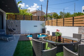 A backyard with a swimming pool, outdoor furniture, a hot tub, and a small garden area. - Private Villa with Pool & Terrace (Gouves)