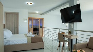 Une chambre d’hôtel avec un lit, un bureau, une télévision et un balcon doté d’une rambarde.