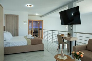 Ein Hotelzimmer mit Bett, Schreibtisch, Fernseher und einem Balkon mit Geländer.