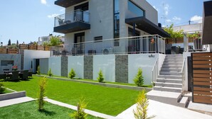 Une maison moderne à deux étages, dotée d’un balcon, d’un escalier et d’une pelouse bien entretenue.