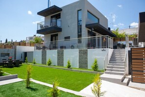 Ein modernes, zweistöckiges Haus mit Balkon, Treppe und gepflegtem Rasen.