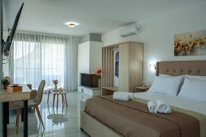 Ein Hotelzimmer mit einem Bett, einem Schreibtisch, einem Stuhl, einem Fernseher, einem Kleiderschrank und einem Bild an der Wand.