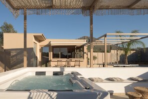 A modern outdoor hot tub area with a pergola, seating, and a view of a house. - Luxury Villa with Jacuzzi for 9 (Gouves)
