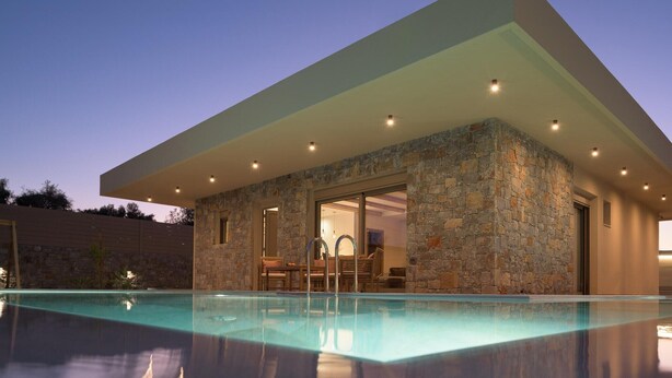 Un edificio moderno con piscina, facciata in pietra e patio coperto.
