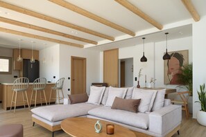 A modern living room with a sectional sofa, wooden beams, pendant lights, and a dining area with bar stools. - Luxury Villa with Jacuzzi for 9 (Gouves)