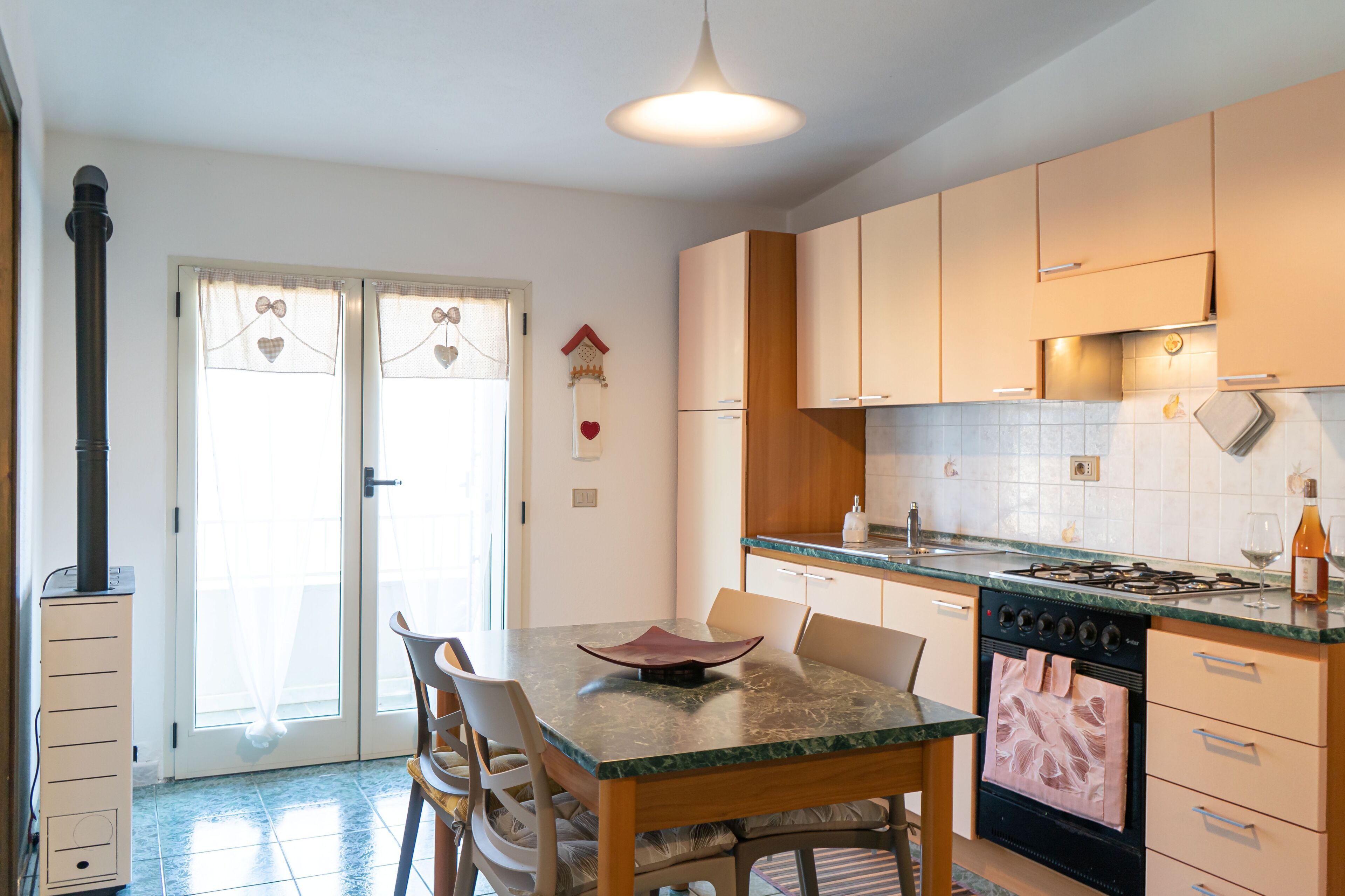 Une cuisine équipée d’une cuisinière, d’un four et de placards. On y trouve également une table à manger avec des chaises.