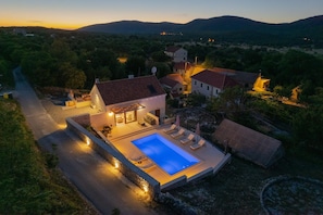 Eine moderne Villa mit Swimmingpool, Sitzgelegenheiten im Freien und Blick auf die umliegende Landschaft.