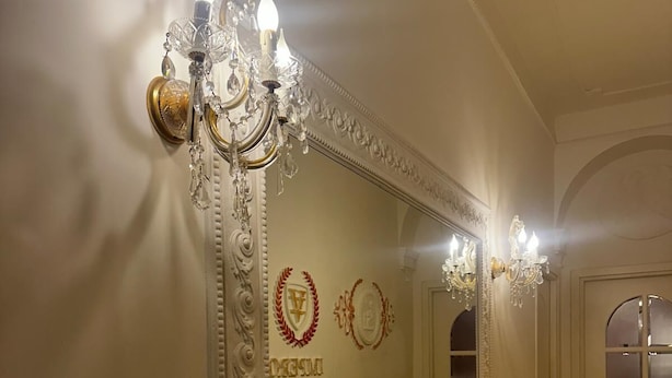 A hallway with a large ornate mirror, two wall-mounted chandeliers, and a door with frosted glass panels. - Impero Vaticano Ottaviano Apartment  (Rome)