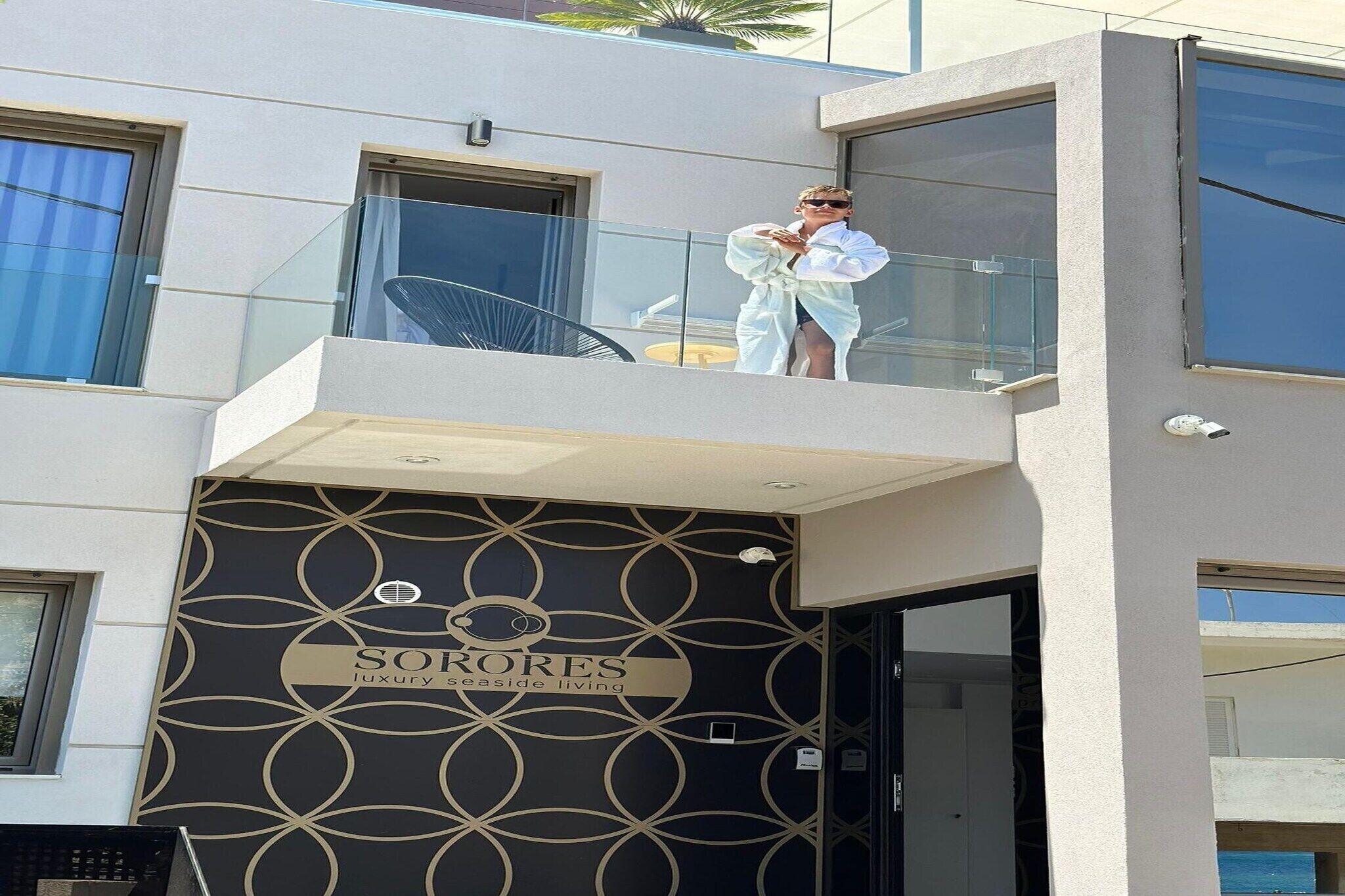 A modern building with a balcony, a sign reading 'SORORES luxury seaside living,' and a geometric pattern on the facade.