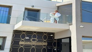 Ein modernes Gebäude mit Balkon, einem Schild mit der Aufschrift 'SORORES luxury seaside living' und einem geometrischen Muster an der Fassade.