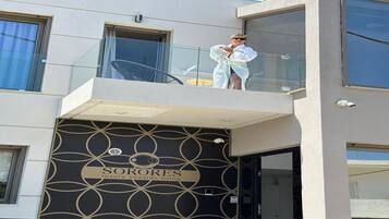 A modern building with a balcony, a sign reading 'SORORES luxury seaside living,' and a geometric pattern on the facade.