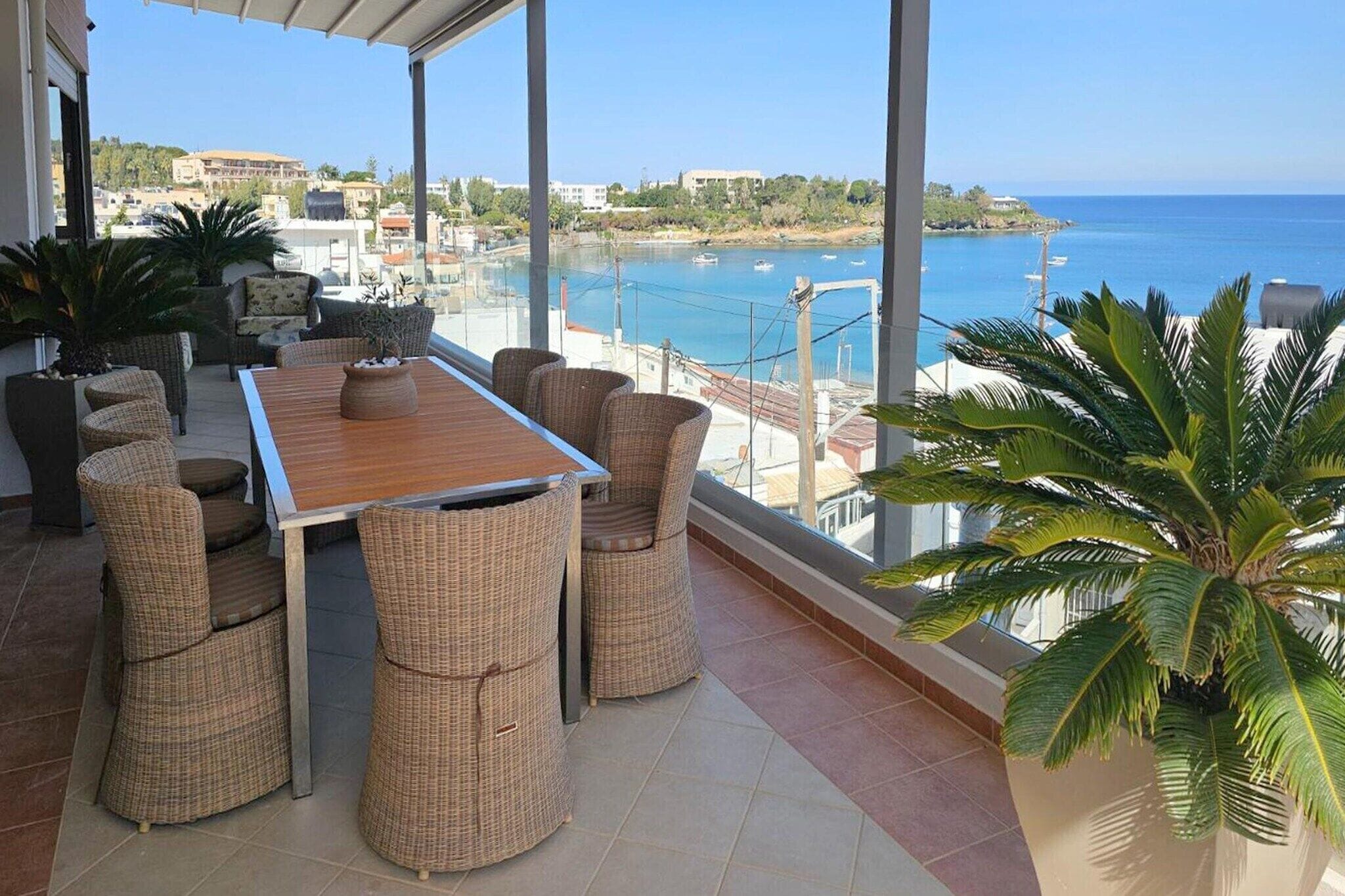 A balcony with wicker furniture, a wooden table, and a large potted plant.