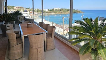 A balcony with wicker furniture, a wooden table, and a large potted plant.