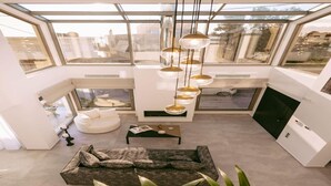 Ein modernes Interieur mit Oberlicht, einer Couch, einem Couchtisch und einer Pendelleuchte.