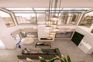 A modern interior with a skylight, a sofa, a coffee table, and a pendant light. - Beachside Villa with Pool in Agia Pelagia (Agia Pelagia)