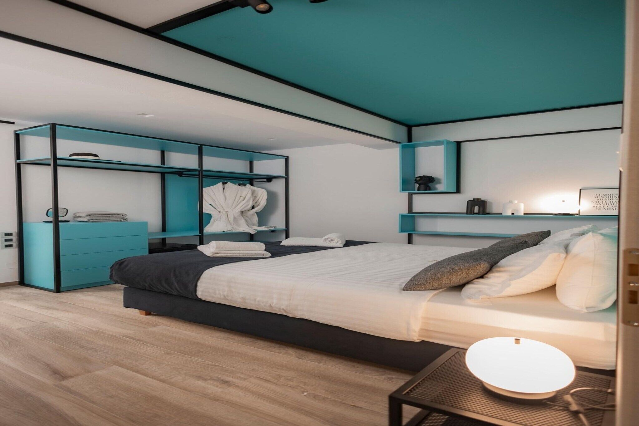 A modern bedroom with a bed, built-in storage, and a bedside table.